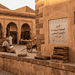 - VeyrZest.com Old stone courtyard with arches, bookshelves, and men reading outdoors at a historic library market during sunset.