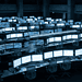 - VeyrZest.com Trading floor with rows of monitors showing stock charts and graphs; a large clock on the wall.