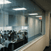 An_elevated_view_looking_down__Nano_Banana_Pro_33889 (1) - VeyrZest.com Open-plan office seen through a glass partition, with employees at desks and computer monitors.