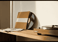 Vinyl records leaning against a wall with a turntable on a wooden shelf, in warm light