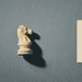 - VeyrZest.com Beige chess knight model on the left casting a shadow, next to a beige notebook page with a black hand-drawn maze against a blue textured background.