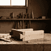 - VeyrZest.com Woodworking bench with chisels and mallet, wood shavings scattered on the table, a window in the background.