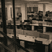 - VeyrZest.com Open-plan office with rows of cubicles and desks, several chairs, and glass barriers in the foreground; no people present.