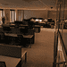 - VeyrZest.com Open-plan office with rows of desks, computer monitors, and cubicle partitions under warm overhead lighting.