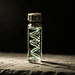 - VeyrZest.com Glass vial with a glowing green spiral coil inside, set on a rough surface against a dark background while lit from the side.