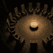 - VeyrZest.com Circular stone chamber with a ring of tall, angular chairs around a central pedestal bearing an envelope on top, in sepia lighting, dramatic shadows.