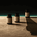 - VeyrZest.com Three amber pill bottles with blank labels placed on a beige textured surface against a dark backdrop with a turquoise glow and a long shadow to the right.