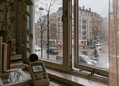 Indoor windowsill with a plant and a decibel meter reading 58 dB, looking out at a rainy city street.
