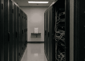 Data center aisle with tall server racks on both sides; cables visible on the right side.