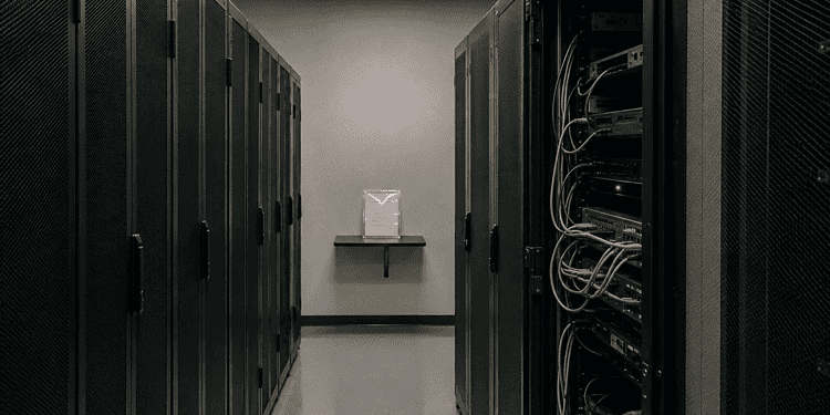 Data center aisle with tall server racks on both sides; cables visible on the right side.