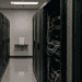 - VeyrZest.com Data center aisle with tall server racks on both sides; cables visible on the right side.